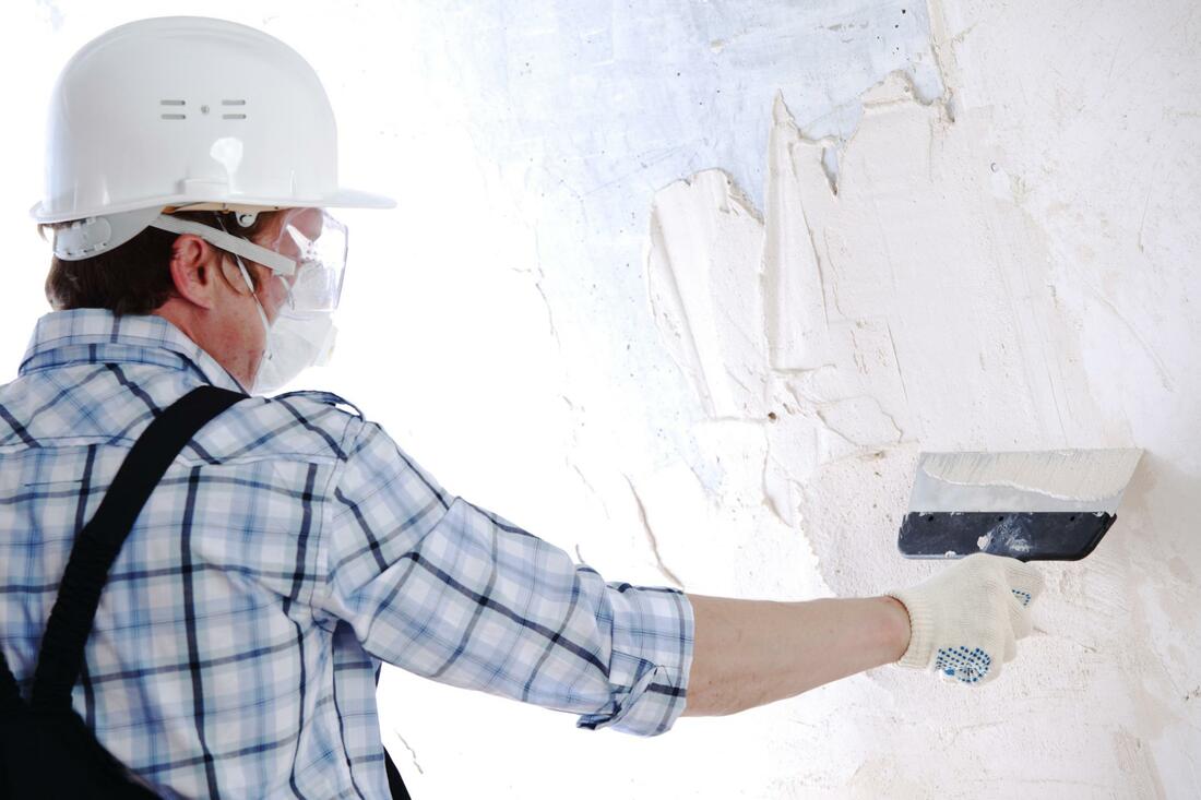 Male worker putting plaster on wall